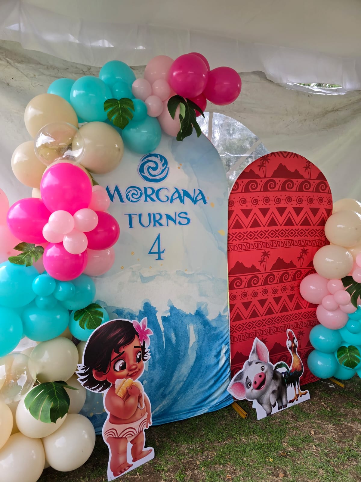 Decoración de evento temático Moana con arcos de globos y mampara