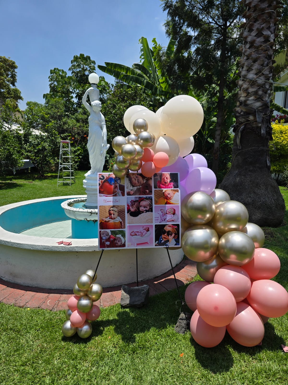 Caballete con fotos y globos metálicos dorados en jardín